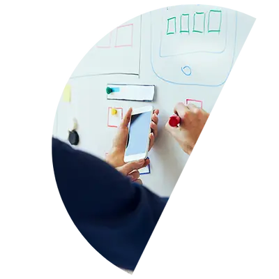 Ręce ze smartfonem przy tablicy z makietami interfejsu